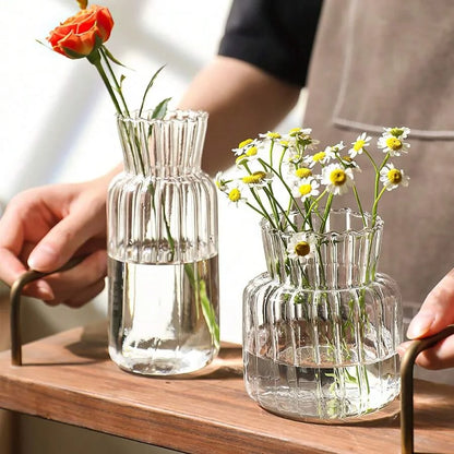 Two transparent glass vases for flowers with fresh blooms, showcasing elegant ribbed design
