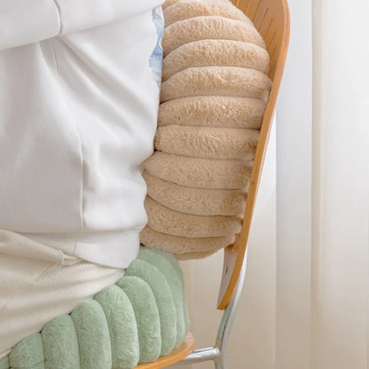 Nutshell beige round pumpkin pillow cushion placed on a wooden chair with a person sitting nearby