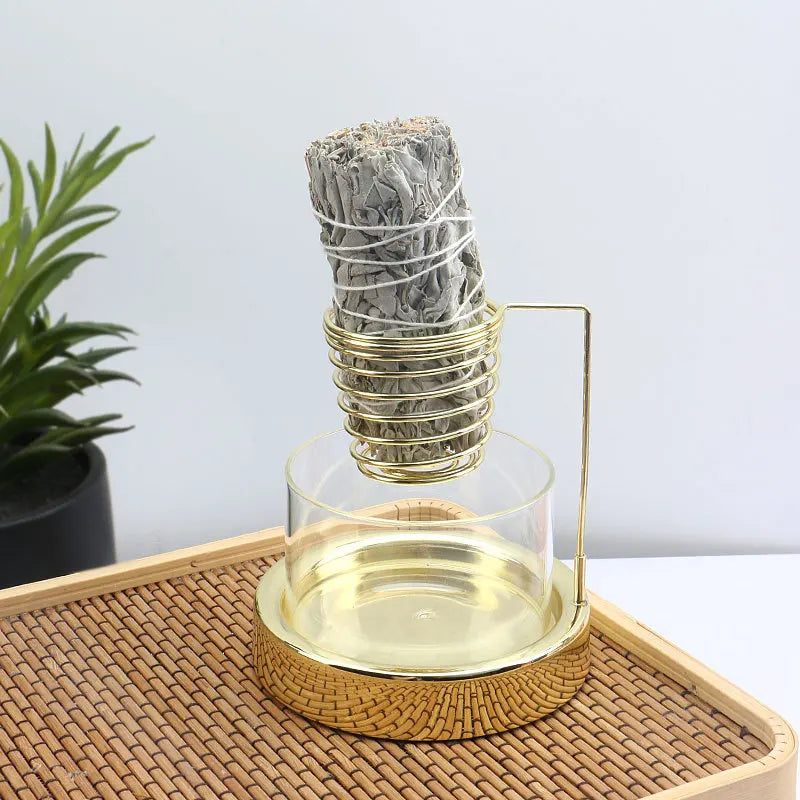 Nutshell gold sage incense burner with glass base holding a burning sage bundle on rattan tray