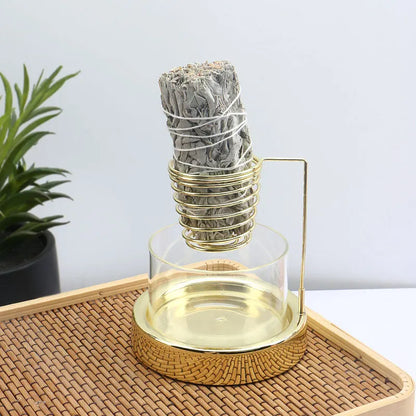 Nutshell gold sage incense burner with glass base holding a burning sage bundle on rattan tray
