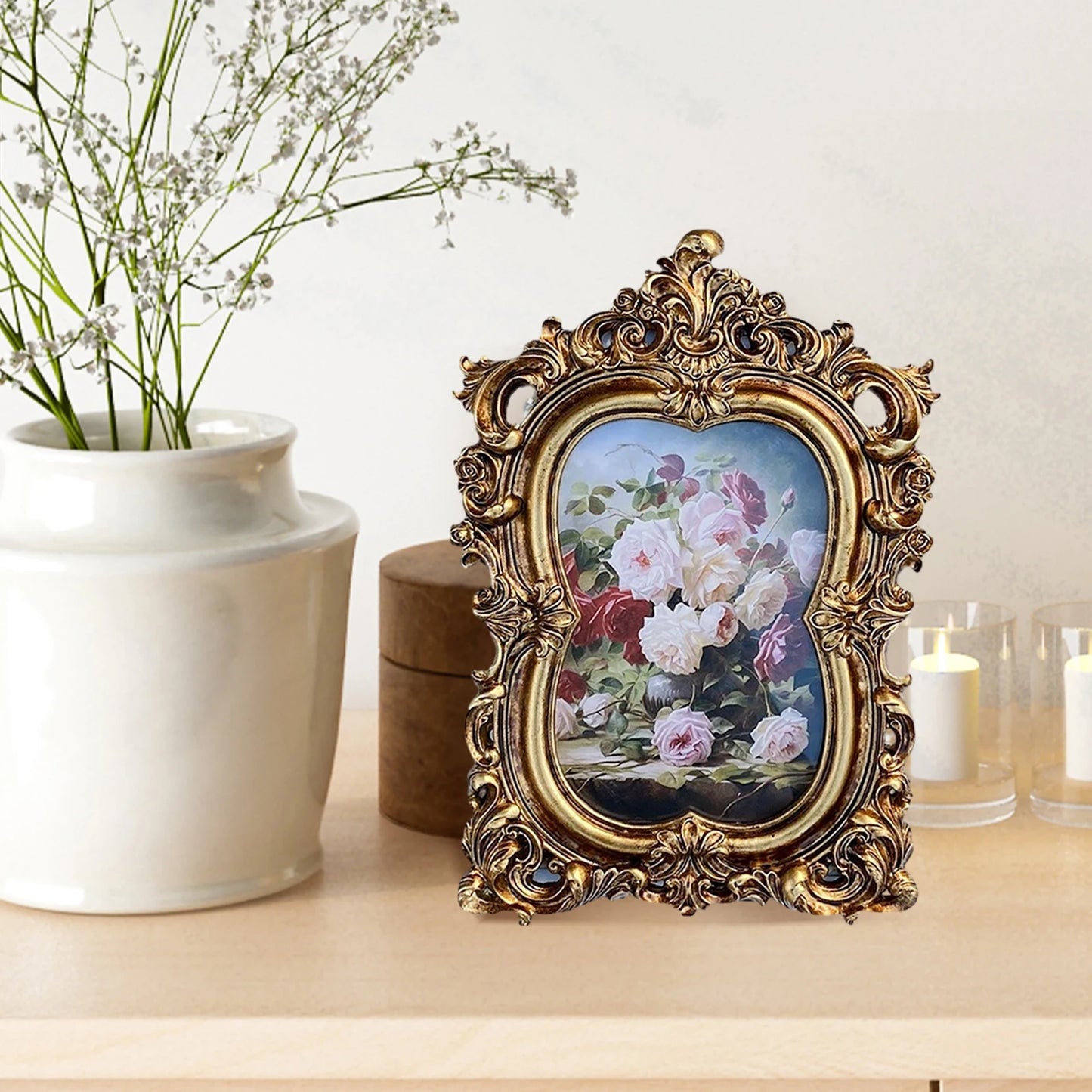 Vintage gold resin photo frame displaying beautiful floral artwork on a wooden table
