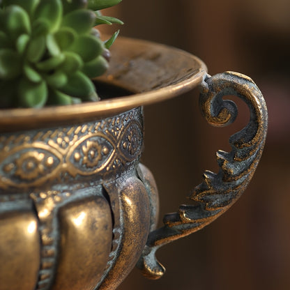 Close-up of vintage wrought iron pot with ornate handle and decorative detailing holding a green succulent