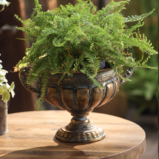 Nutshell vintage wrought iron pot vase with intricate design holding green fern on wooden table
