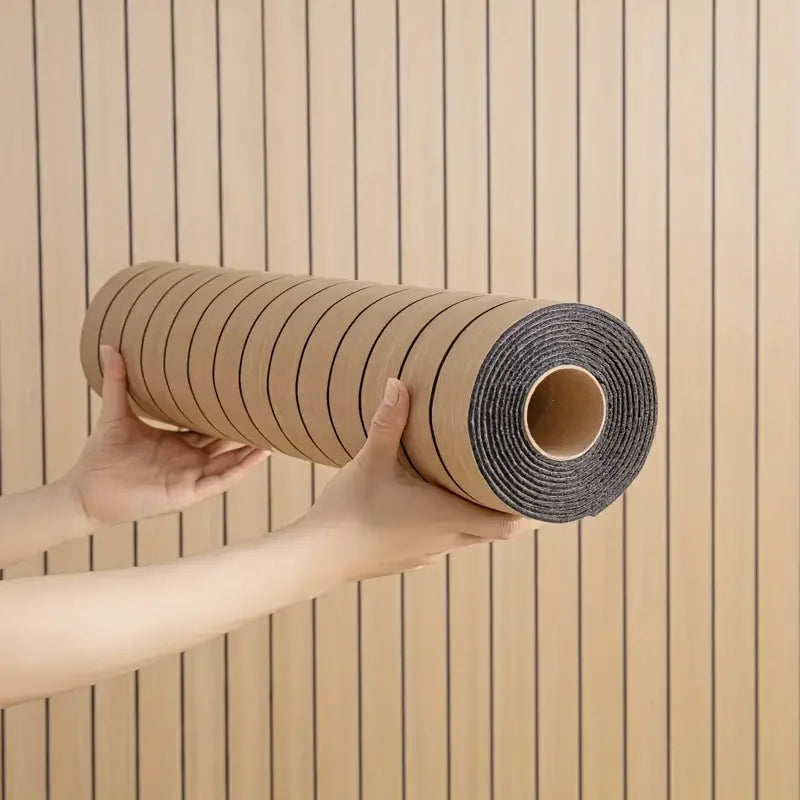 Nutshell woodgrain wallpaper roll with vertical dark pinstripes held by hands against installed wall