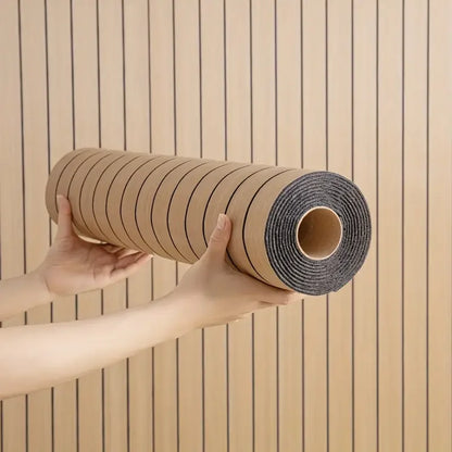 Nutshell woodgrain wallpaper roll with vertical dark pinstripes held by hands against installed wall