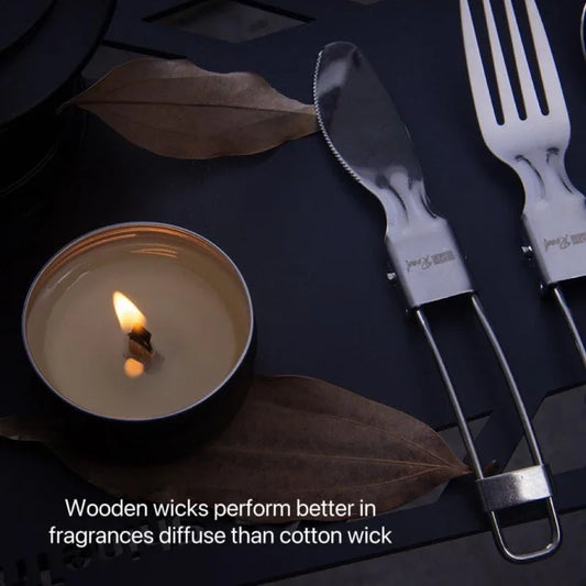 Nutshell candle with wooden candle wick burning next to grilling utensils and dried leaves