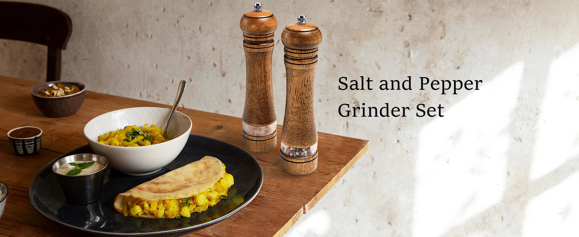 Nutshell wooden salt and pepper grinder set on kitchen table with food plates in background