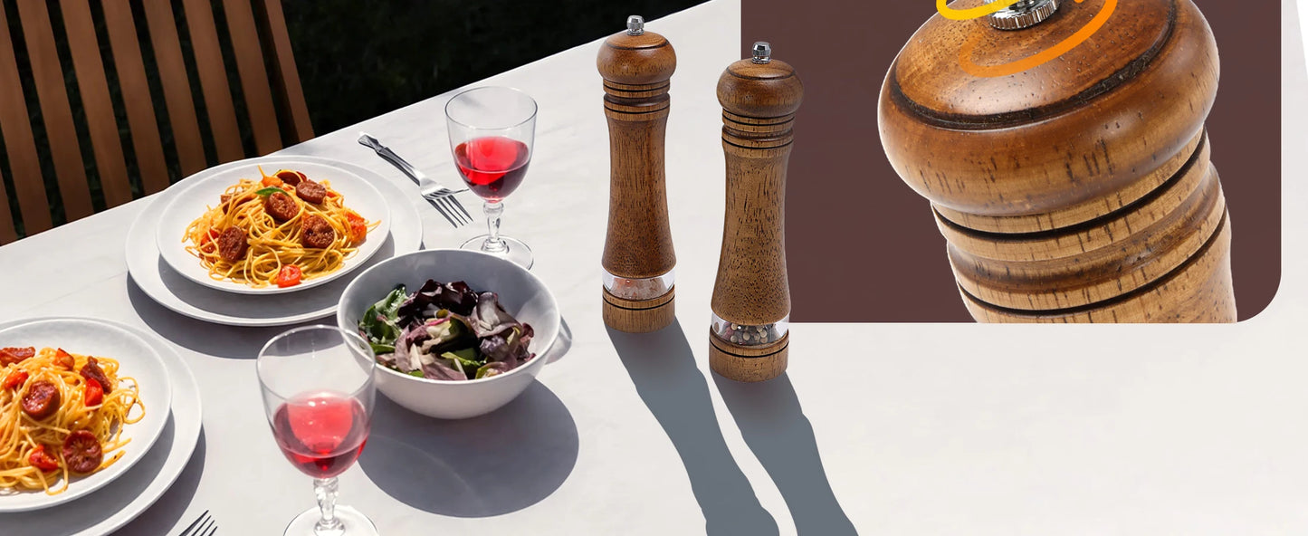 Nutshell wooden salt and pepper grinder set displayed on table next to pasta dishes and wine glasses