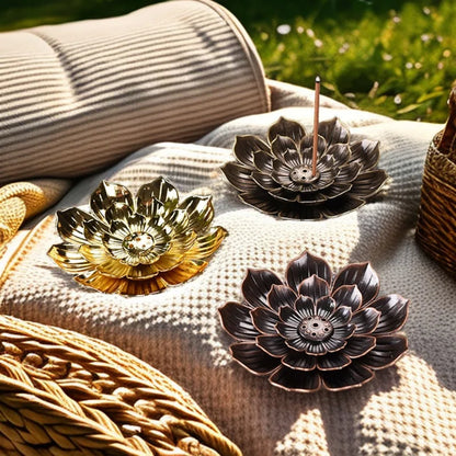 Nutshell Zen lotus incense burner trio in gold, bronze, and black metal on textured outdoor fabric