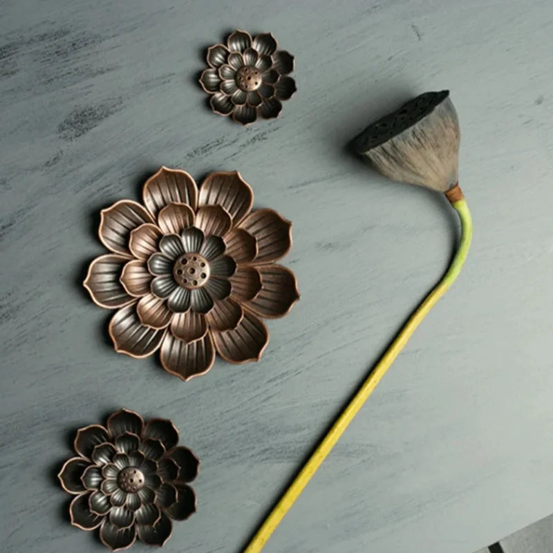 Nutshell Zen lotus incense burner with three bronze lotus flower holders on gray surface